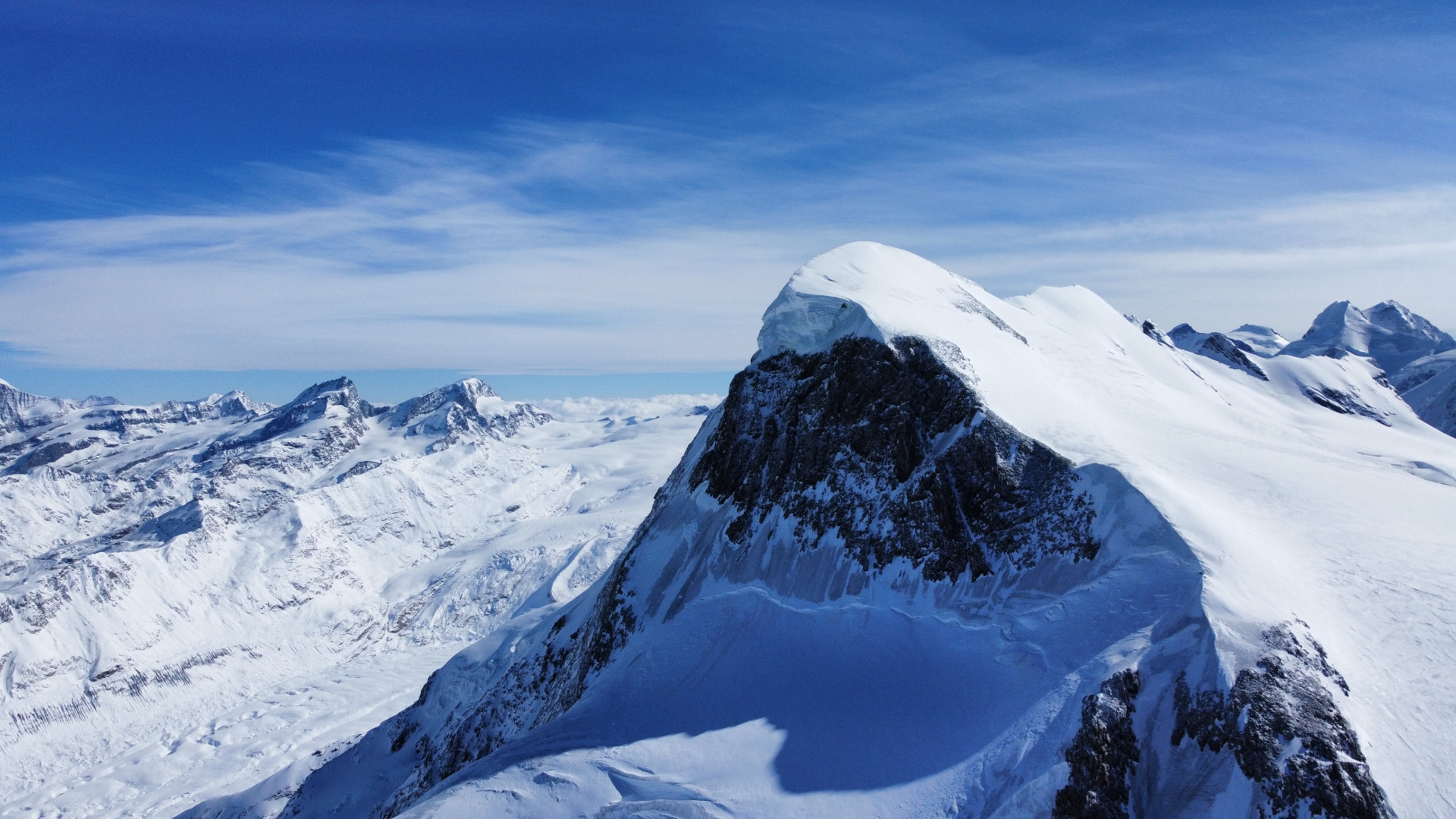 Snow-covered Alpine summit above a sea of clouds — aerial view, Zermatt